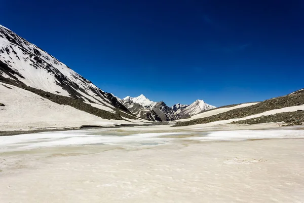 Hindistan 'ın Zanskar bölgesinin uzak yüksek rakımlı yabanda mavi gökyüzünün altında Himalayalar' a ait geniş bir kar tarlası ve dağ zirveleri..