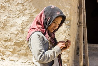 Zanskar, Hindistan - Temmuz 2012: Zanskar 'da bir köyde kır çamurlu evinin önünde duran genç bir Hintli kızın samimi portresi.