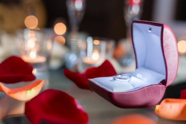 Altın yüzük, kırmızı kutuda alyans ve beyaz-kırmızı arka planda kırmızı kalp ve güzel bir bokeh. Düğün anı, yıldönümü, nişan, ya da Sevgililer Günü. Mutlu gün