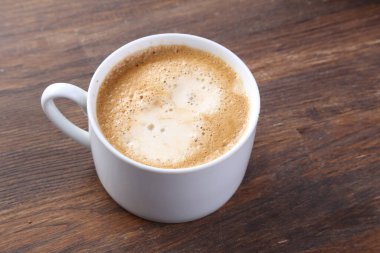 Beyaz ahşap zemin üzerinde bisküvi olan sütlü kahve.