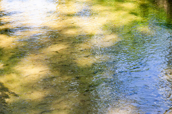 sun glare on the wavy surface of the water against the background of the sandy bottom.