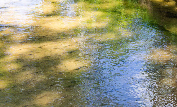 sun glare on the wavy surface of the water against the background of the sandy bottom.