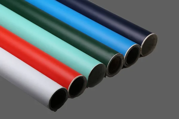 Row of various multicolored vinyl films or plotter cutting film rolls on grey background wide panorama banner.