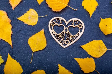 Wooden inscription love on a black stone background with yellow leaves. Autumn concept