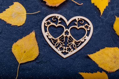 Wooden inscription love on a black stone background with yellow leaves. Autumn concept