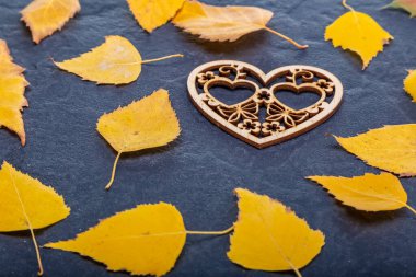 Wooden inscription love on a black stone background with yellow leaves. Autumn concept