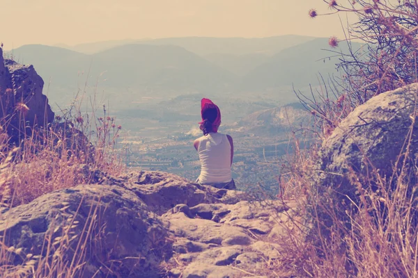 Vintage photo of young woman seating on the edge on the mountain — Stock Photo, Image