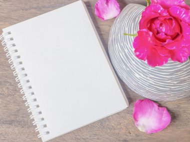 Not defteri ve vazo içinde pembe Gül