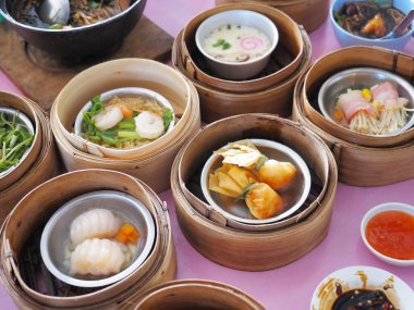 Dim sum Çin buharlı yemeği pembe masada bambu kabında.
