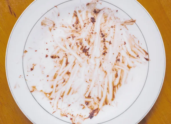 Beyaz tabakta yenmiş çikolata sosunu ahşap arka planda kapatın..