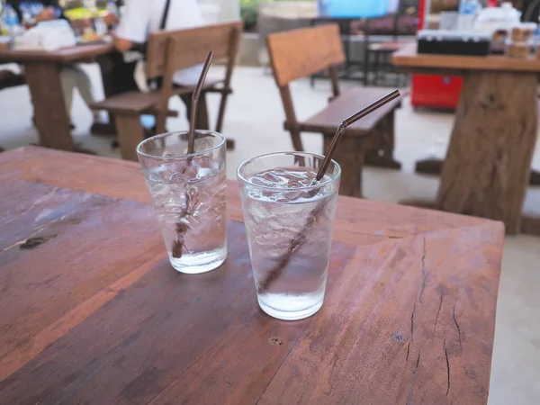 Glass of water with ice on the wood table in restaurant .