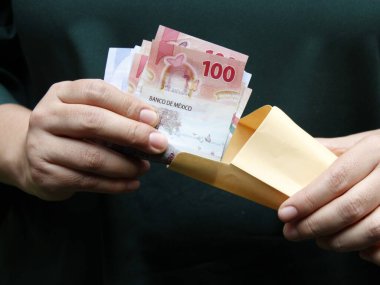 Meksikalıların parasını kağıt zarfta saklayan bir kadının eli.