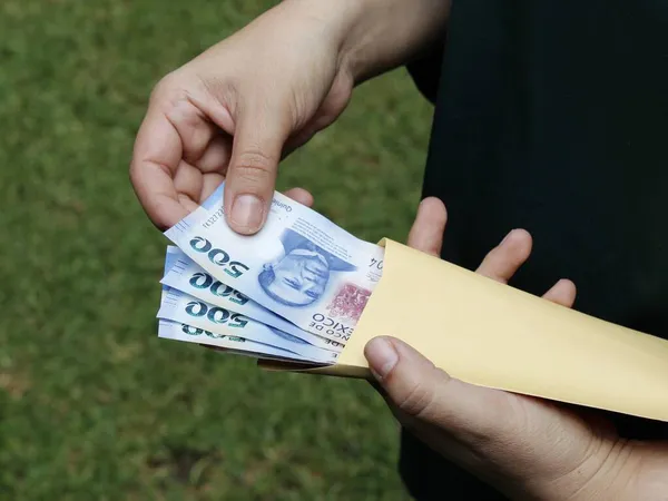 Meksikalıların parasını kağıt zarfta saklayan bir kadının eli.