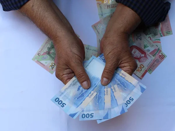 500 pezoluk Meksika banknotları tutan yaşlı bir adamın elleri.
