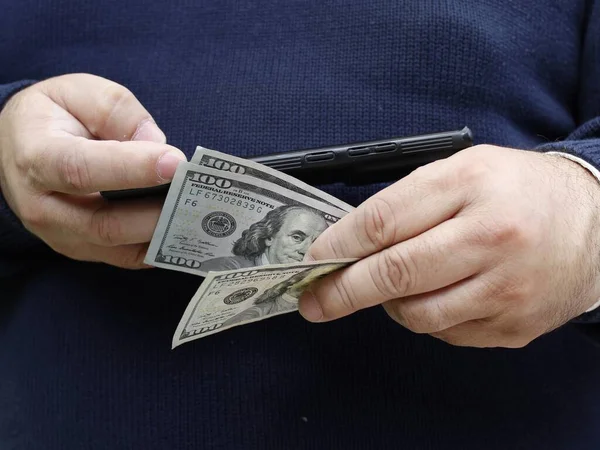 一个拿着美元钞票和智能手机的人的手 — 图库照片