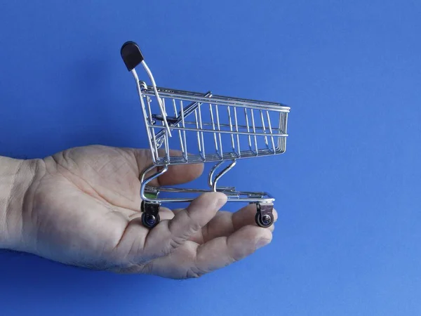 Mão Homem Segurando Carrinho Compras Fundo Azul — Fotografia de Stock