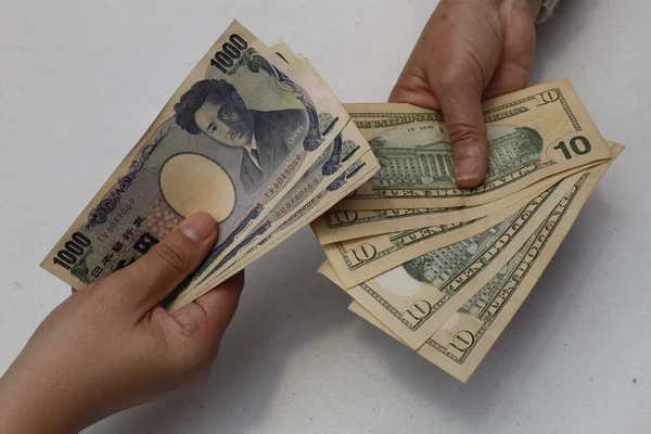 Hands Exchanging Japanese Banknotes American Dollars Bills — стоковое фото