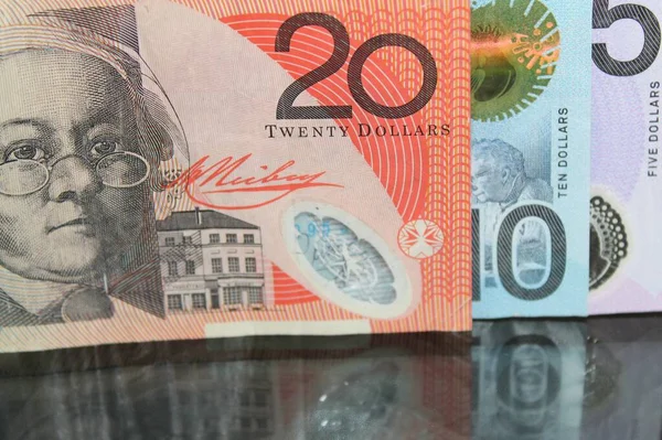 approach to australian banknotes on a glass table with reflection