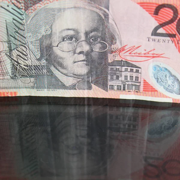 approach to australian banknote on a glass table with reflection