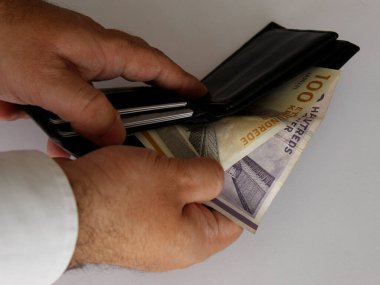 hands of a man holding danish bills and a black leather wallet