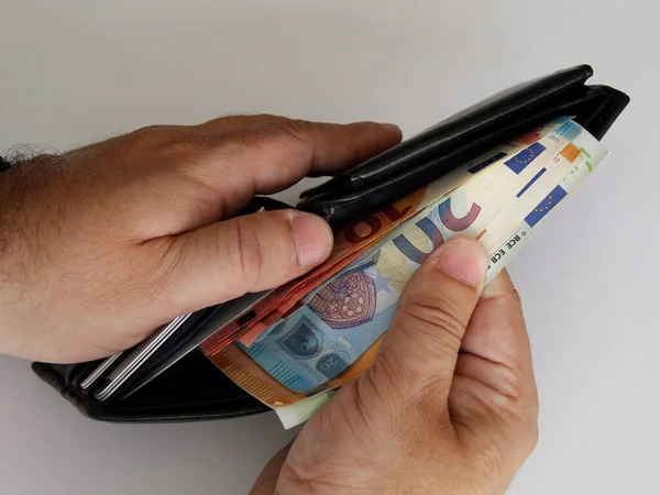 hands of a man holding european bills and a black leather wallet