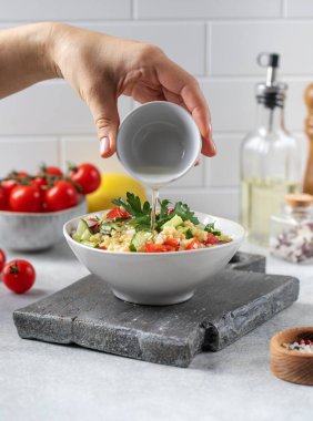 Kadın sebzeye yağ döker, bulgur salatası da beyaz masaya.