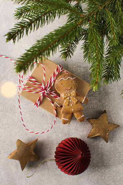 Presents and gingerbread man lie on grey background with Christmas tree branches