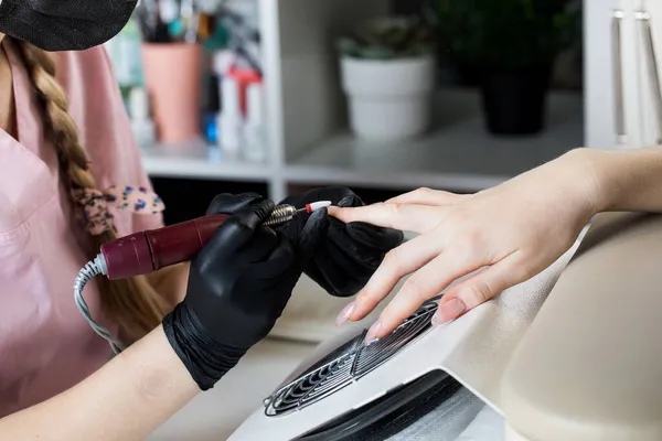 Manikiurzystka usuwa lakier żelowy z paznokci za pomocą frezu. Manicure sprzętowy zbliżenie. Powłoka szelaku na gwoździach — Zdjęcie stockowe