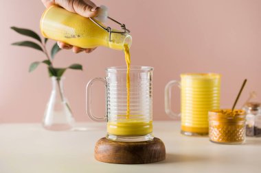  Pembe zemin üzerine zerdeçal dökülmüş altın latte. Daha iyi uyumak için ay sütü. Ayurvedik içeceği.