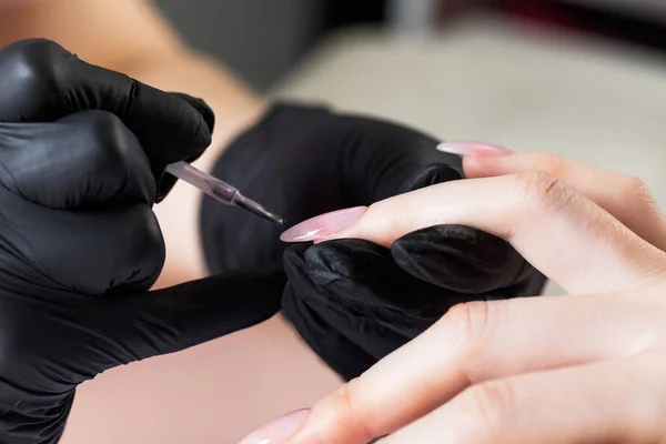 Manicure proces in een schoonheidssalon. De manicure verft de nagel met vernis. — Stockfoto