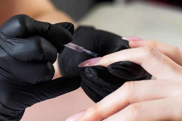 Proceso de manicura en un salón de belleza. La manicura pinta la uña con barniz. —  Fotos de Stock