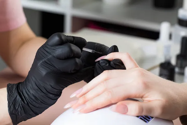 Maniküre im Schönheitssalon. Der Maniküre lackiert den Nagel mit Lack. — Stockfoto