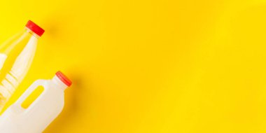 Kırmızı kapaklı plastik şişeler sarı arka plan pankartıyla tasarım için boşluk