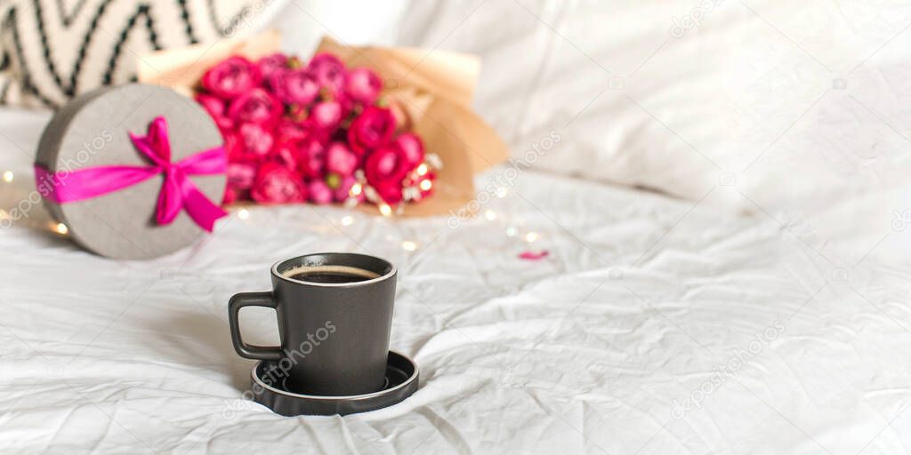 Cup of aromatic coffee gift and roses bouquet with fairy lights on bed banner