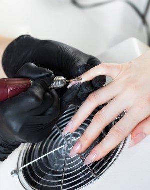  Donanım manikürü. Manikür işlemi, tırnak etlerini kesiciyle aldırma. Elektrik dosyası ile çiviler işleniyor.