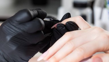 Güzellik salonunda manikür işlemi. Manikürcü ojeyle oje sürüyor..