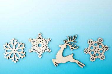  Noel arkaplanı ahşap kar taneleri ve gradyan mavi arka planda bir geyik. Boşluğu kopyala.