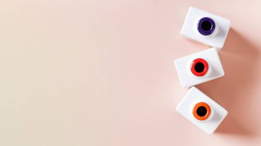 Renkli cila şişeleri açık pembe arka planda duran tırnak kabukları. Uzayı kopyala Pankart