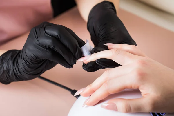 Maniküre behandelt den Nagel des Kunden mit einer entfettenden Flüssigkeit, um die Nägel für die Maniküre vorzubereiten, um die klebrige Schicht zu entfernen. — Stockfoto