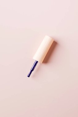 Açık pembe arka planda ojeli mor bir fırça. Boşluğu kopyala.