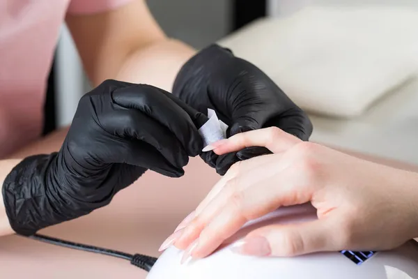 Manicure behandelt de klanten nagel met een ontvettende vloeistof om nagels te bereiden voor manicure, om de kleverige laag te verwijderen. — Stockfoto