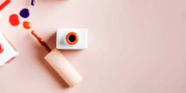 Açık pembe arka planda parlak tırnak cilası şişelerinin farklı renk fırçaları. 