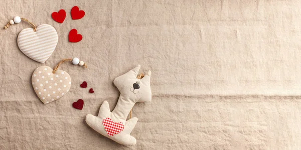 Corações e brinquedo gato no fundo têxtil bege Banner dia dos namorados — Fotografia de Stock