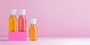  Duş jeli çok renkli plastik şişeler, pembe arka planda çocuklar ve yetişkinler için şampuan. Boşluğu kopyala.