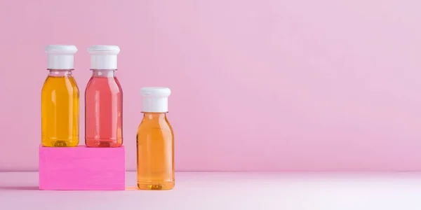Mockup vícebarevné plastové láhve se sprchovým gelem, šampon pro děti a dospělé na růžovém pozadí. Kopírovat prostor. — Stock fotografie
