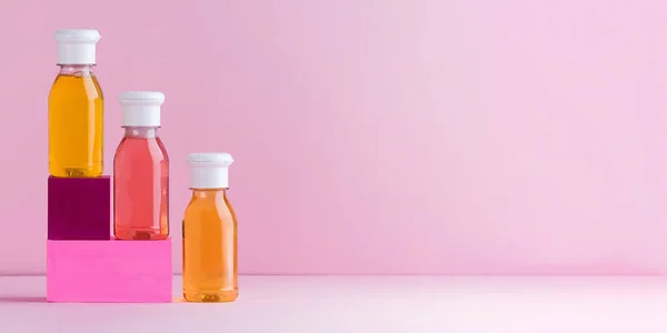 Mockup multicolored plastic bottles with shower gel, shampoo for children and adults on a pink background. Copy space. — Stock Photo, Image