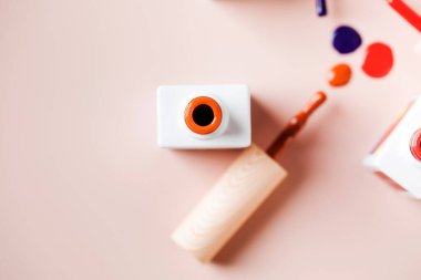 Açık pembe arka planda parlak tırnak cilası şişelerinin farklı renk fırçaları. 