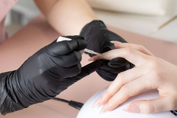 Manicure w salonie piękności. Manikiurzystka maluje paznokieć lakierem. — Zdjęcie stockowe