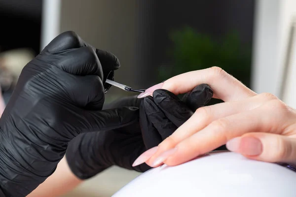 Manicure proces in een schoonheidssalon. De manicure verft de nagel met vernis. — Stockfoto