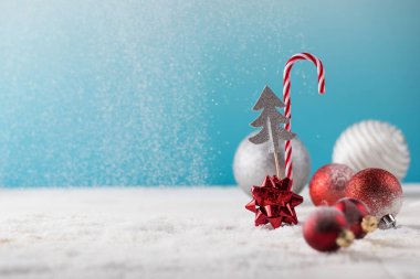 Noel bol bol şekerle süslenir ve kar yağan yapay karın üzerinde kırmızı toplar. Boşluğu kopyala.